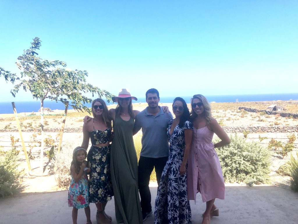 A small group of guests at a Santorini vineyard on a private tour, with the sea behind them